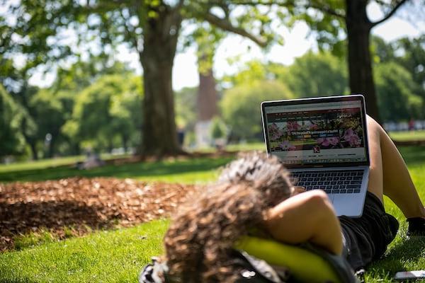 A student relaxes on the quad with her laptop.